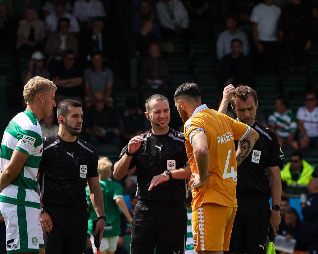 Referee Rob Massey-Ellis speaks with Hartlepool United captain Tom Parkes during the coin toss whilst Yeovil Town captain Jake Wannell looks on.