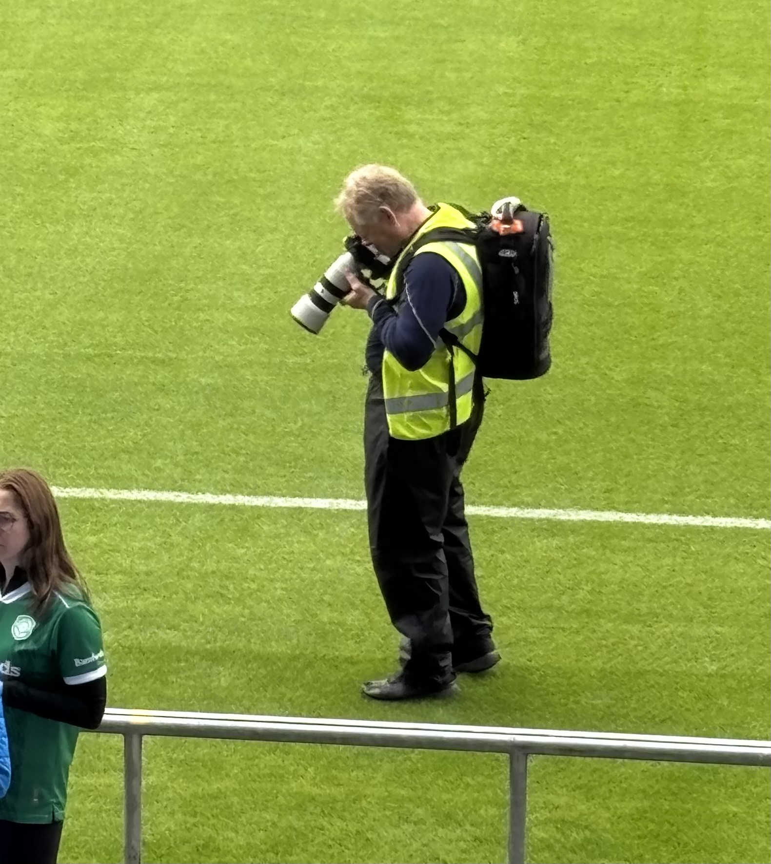 A cameraman with a long lens camera taking a photograph of the new pitch at The Shay.